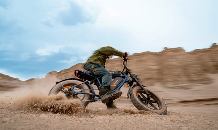 a man wearing helmet rides an engwe m20 2.0 mtb in the sand