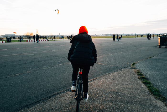 a people with a red hat riding a bike on the road