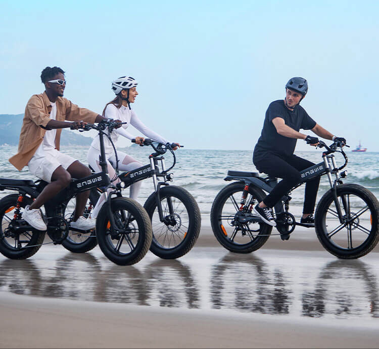 3 people riding fat tire electric bikes on the beach