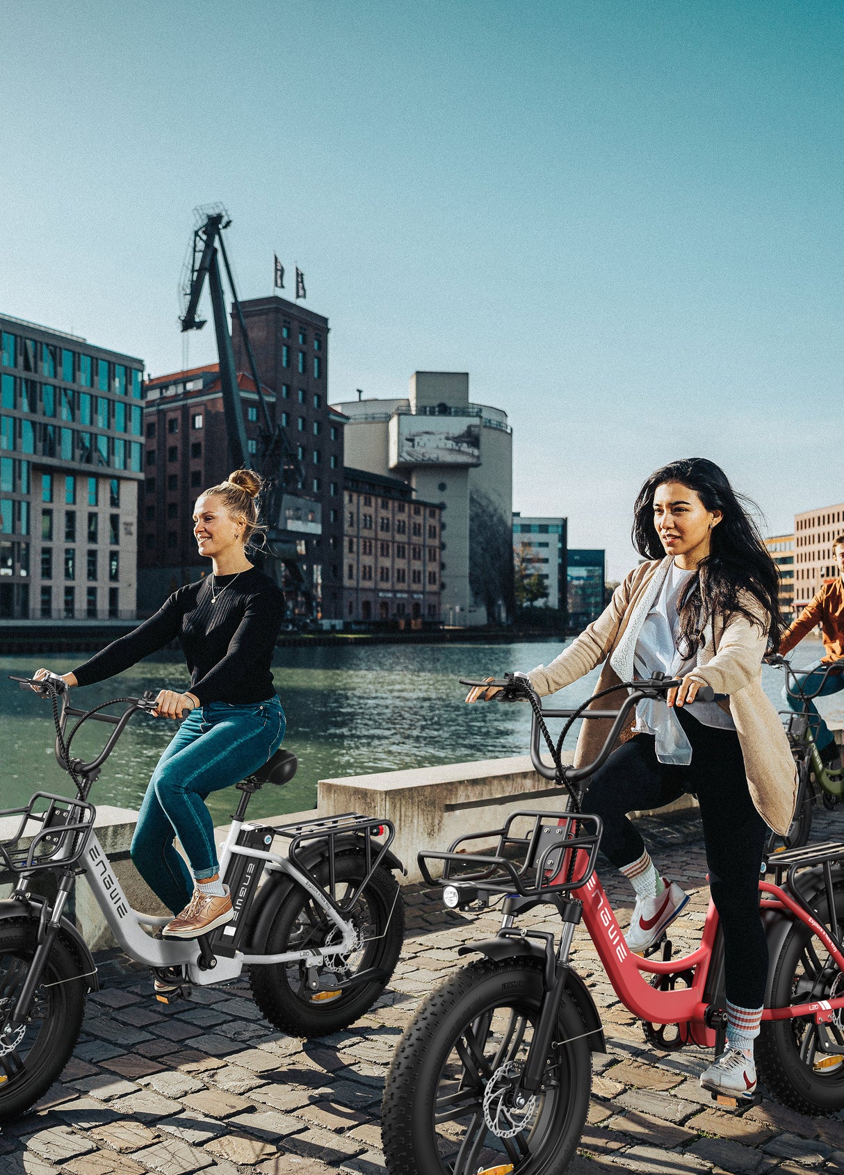 2 women ride a snow white and a flamingo pink engwe l20 fat tire electric bikes by the river