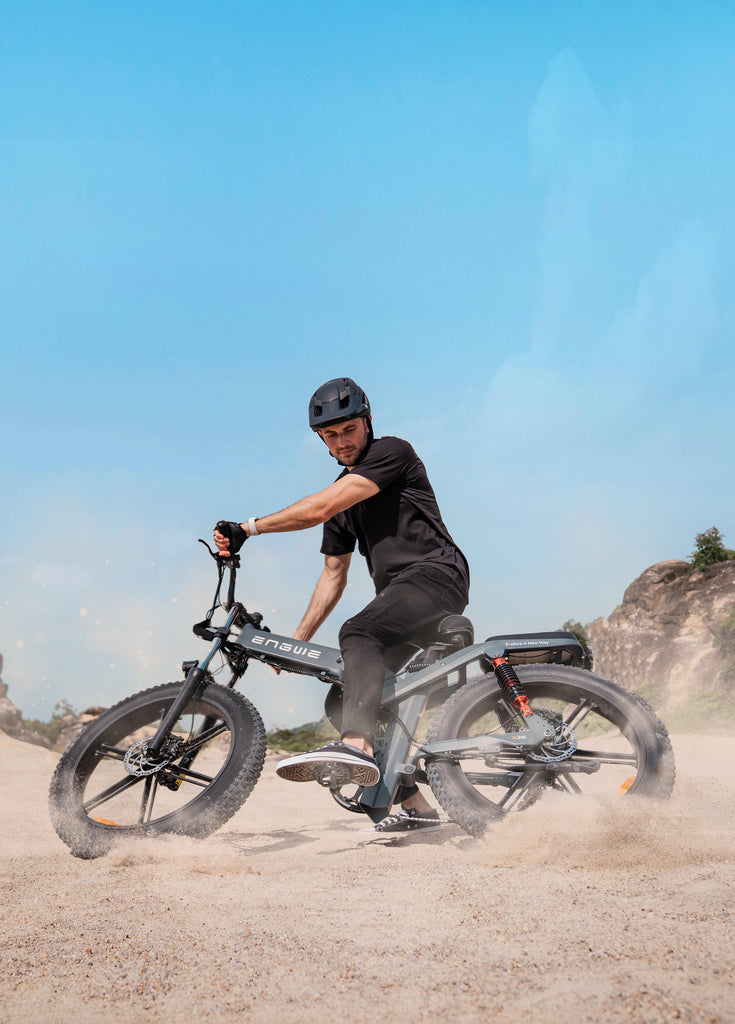 a man rides a black engwe x26 electric mountain bike on the sand